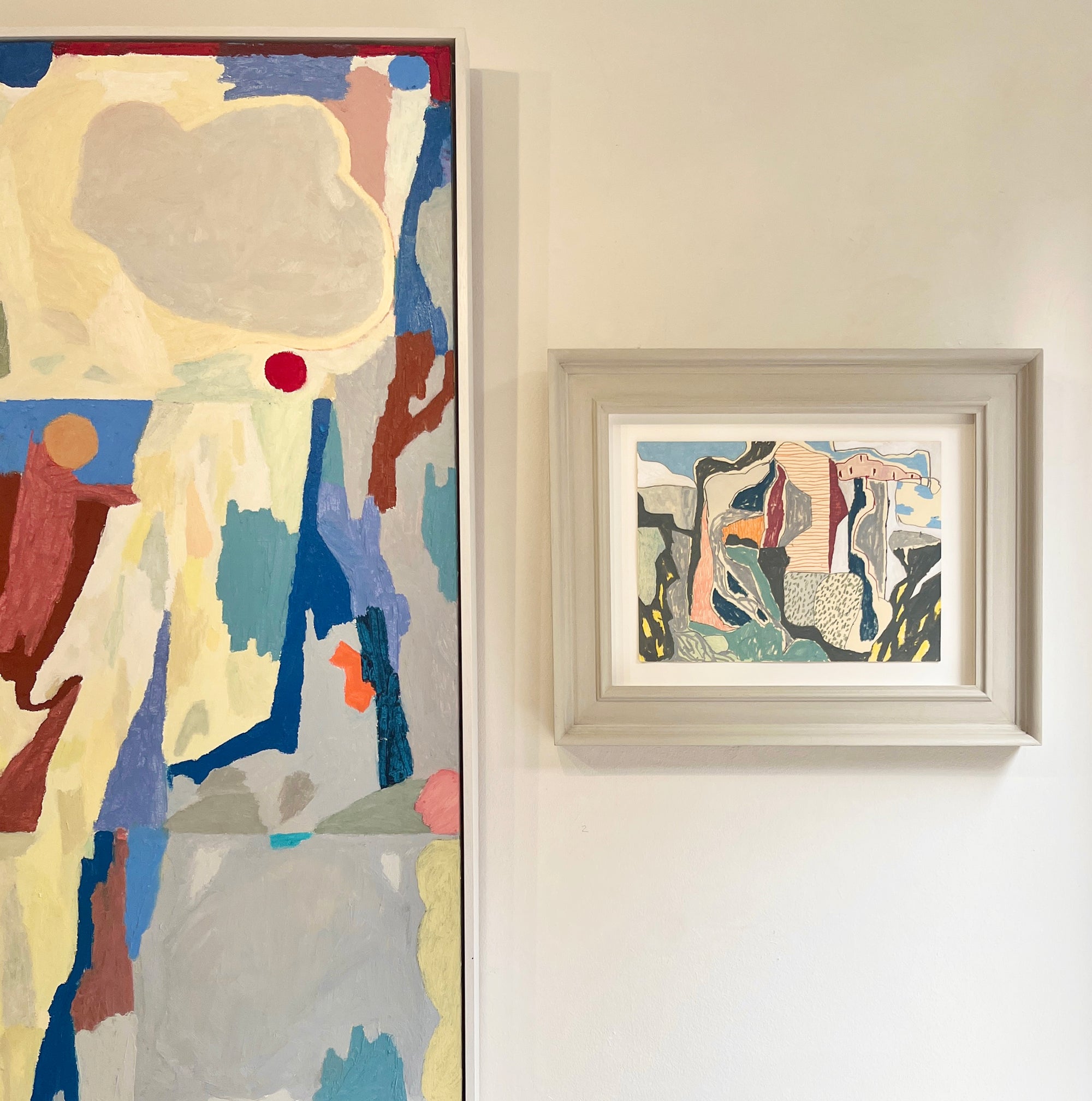 Two abstract artworks on a wall, one large and one small, both featuring colorful abstract designs.