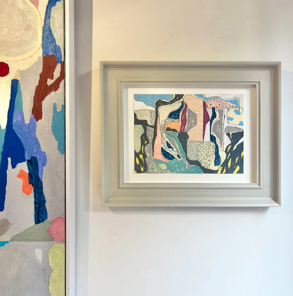 Framed abstract artwork featuring shapes in grays and blues predominantly on a wall in a gallery.