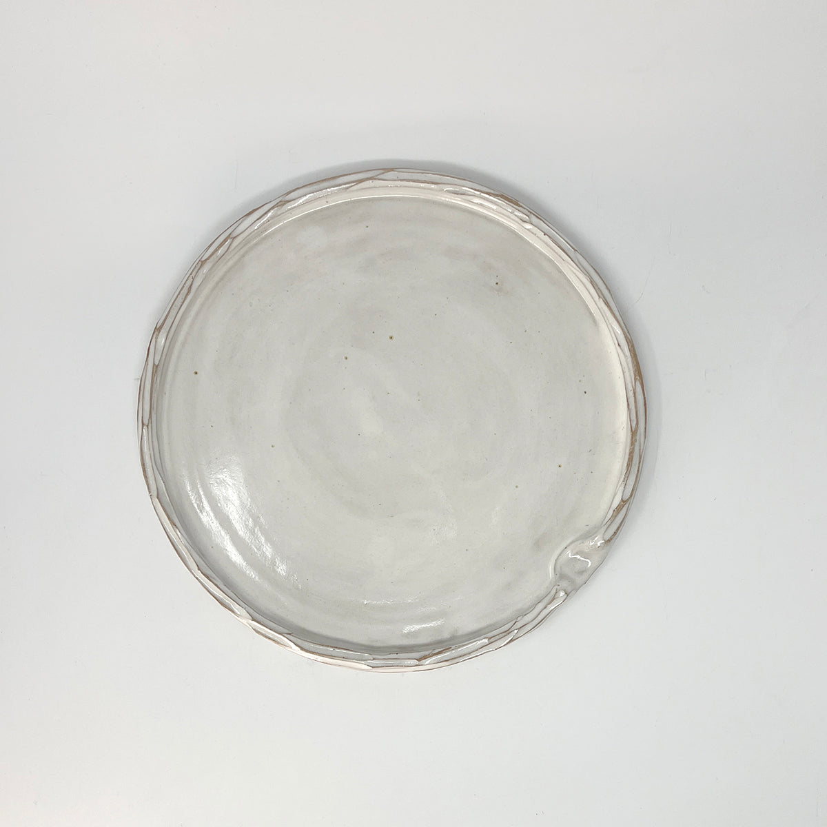 Simple carved white glazed ceramic platter, with indent for thumb. 