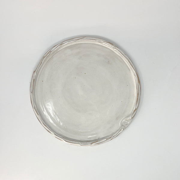 Simple carved white glazed ceramic platter, with indent for thumb. 