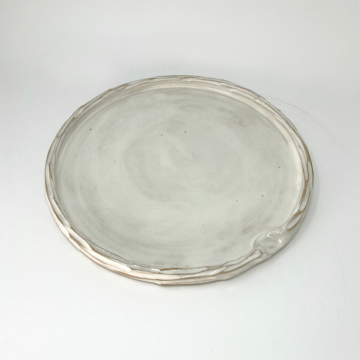 Simple carved white glazed ceramic platter, with indent for thumb. 