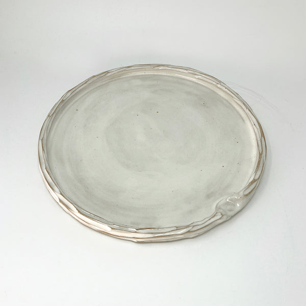 Simple carved white glazed ceramic platter, with indent for thumb. 