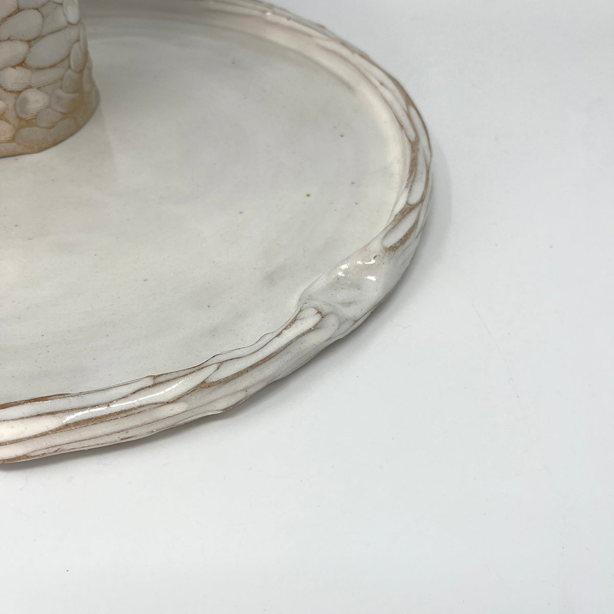 Close up of Simple carved white glazed ceramic platter, with indent for thumb. 