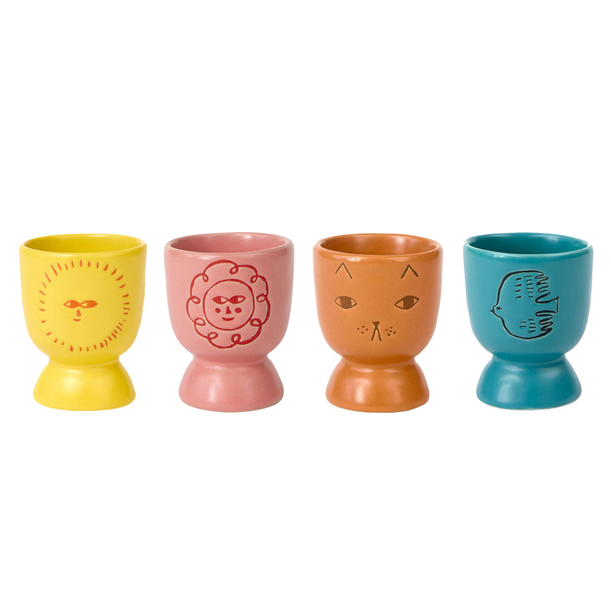 Four ceramic egg cups in yellow, pink, orange, and teal, each decorated with a minimalist face illustration, arranged in a row against a white background. Sunshine, flower, cat and bird designs.