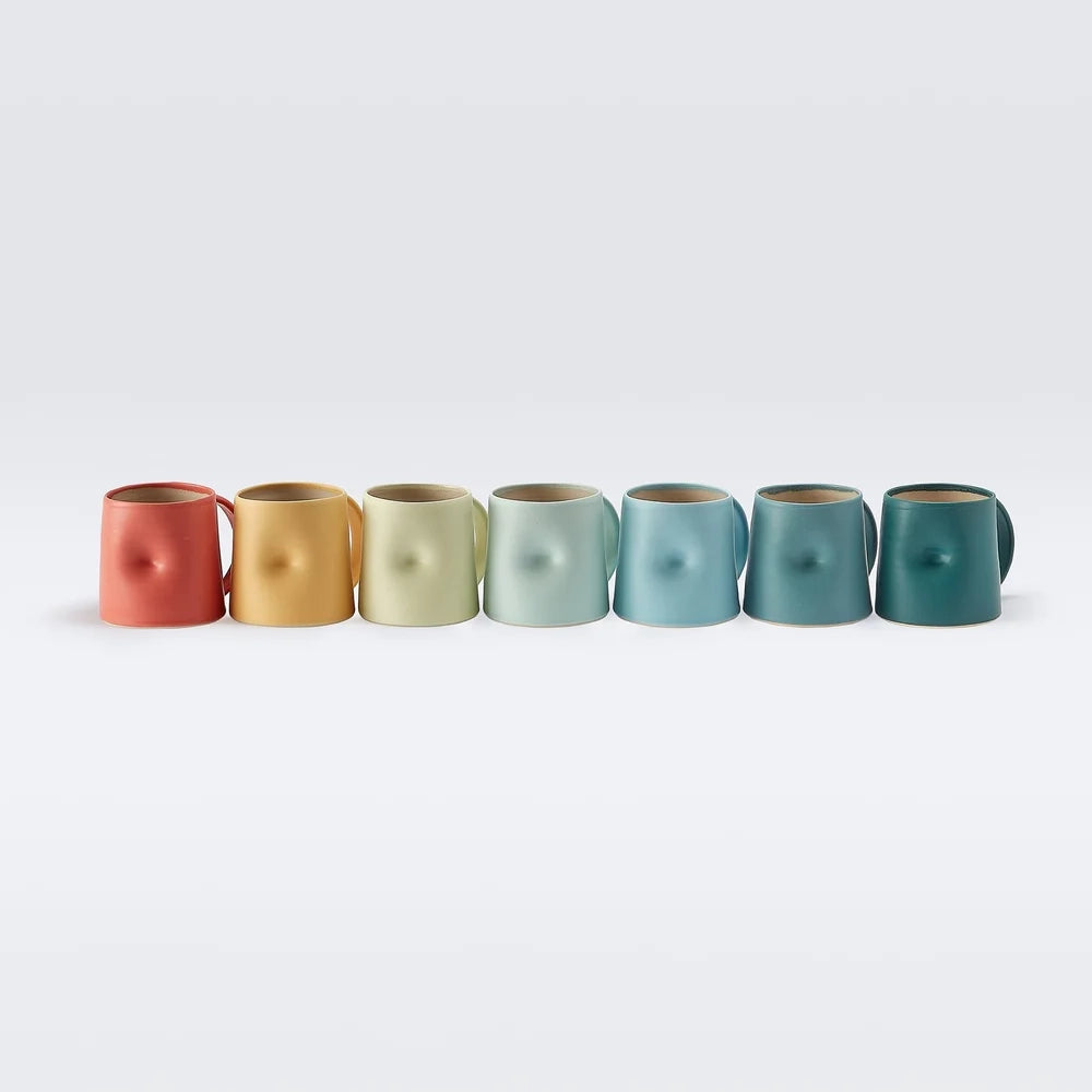A set of colourful ceramic cups in a range of colourson a white background