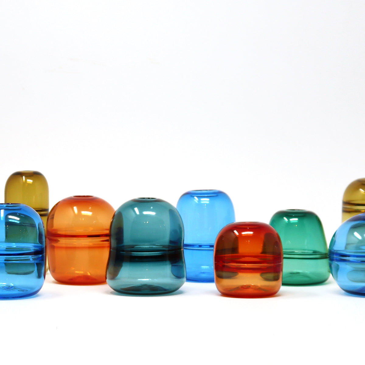 a wide selection of Colourful glass bud vases on a white background