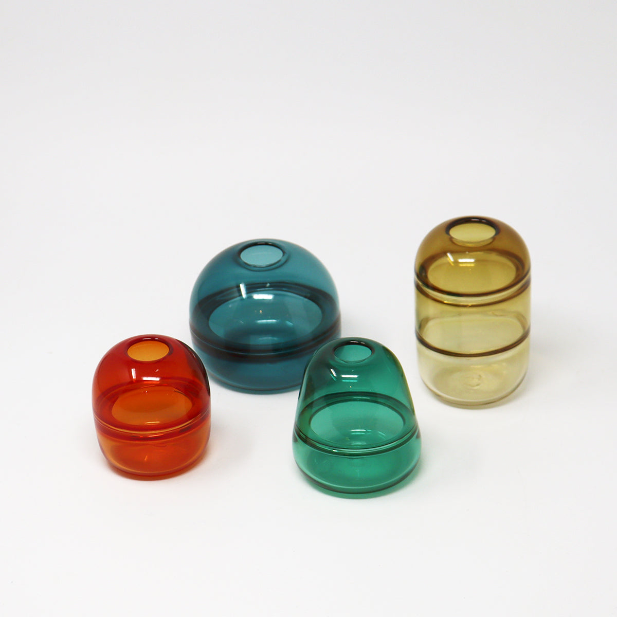 Four colourful glass bud vases on a white background