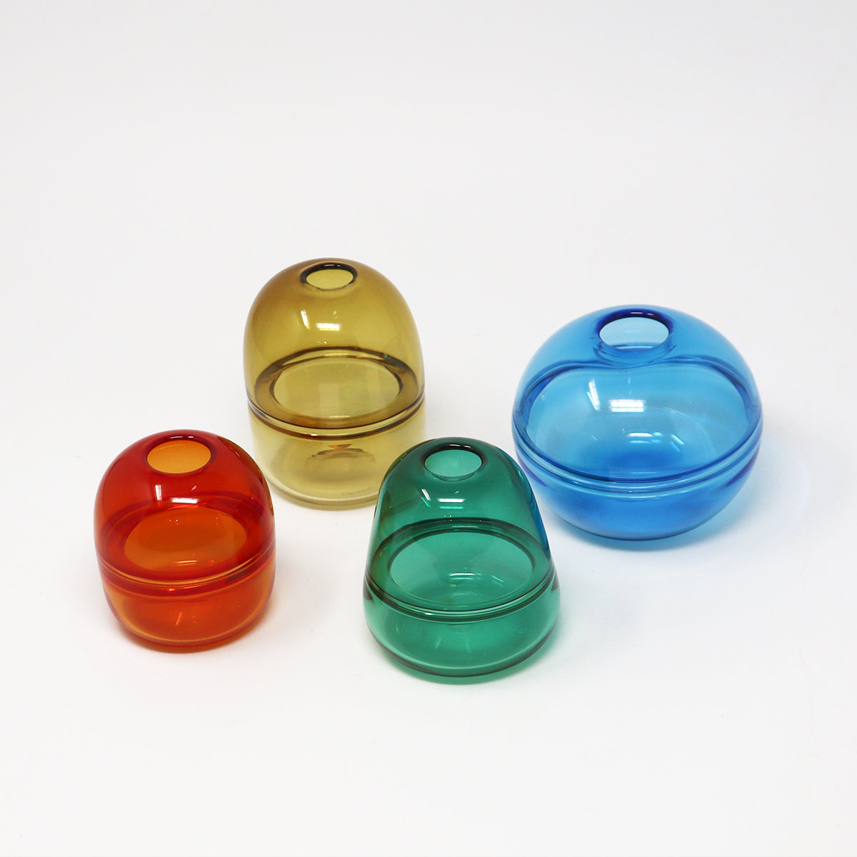 Four colourful hand blown glass bud vases on a white background Emma Baker
