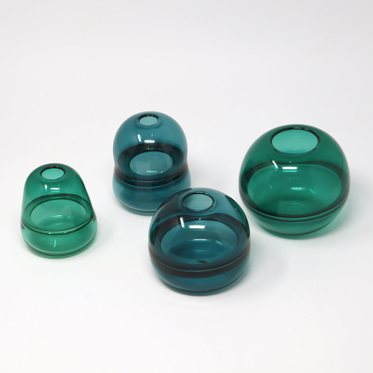 Set of four green glass vases on a white background Emma Baker