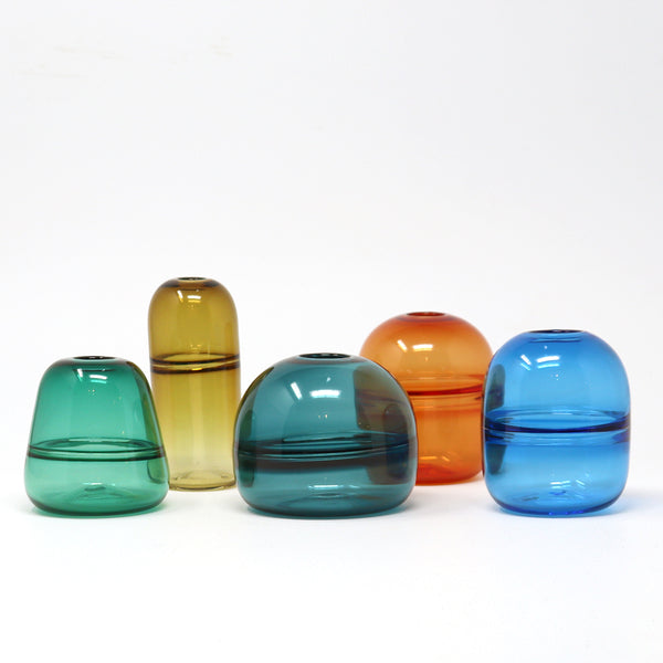 Set of colourful hand blown glass bud vases on a white background emma baker 