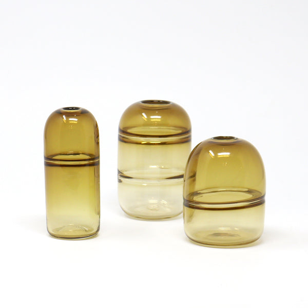 Three amber glass vases of different sizes on a white background
