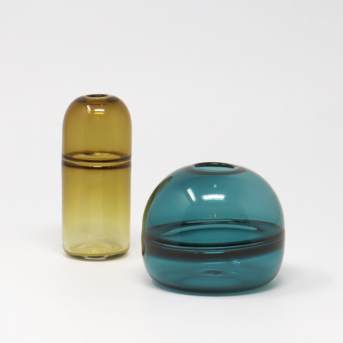 Two glass vases, one amber and one aquamarine, on a white background