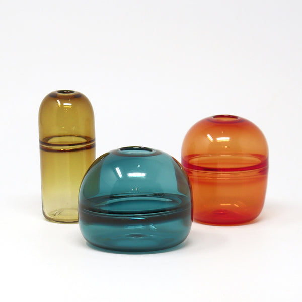 Three colourful hand blown glass bud vases on a white background Emma Baker amber red pine green