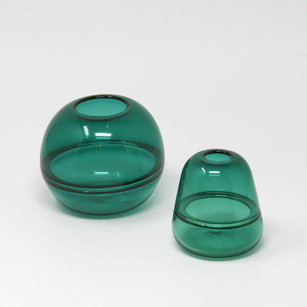 Two green hand blown glass bud vases on a white background