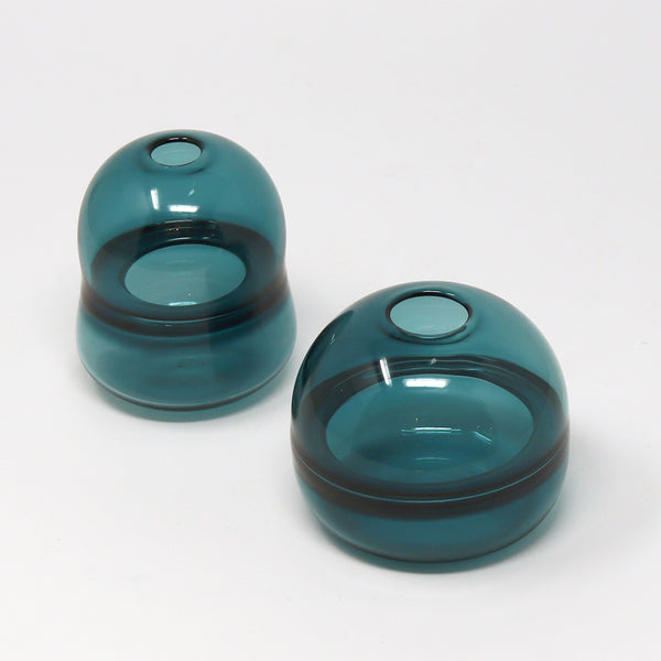 Two teal glass bud vases by Emma Baker on a white background