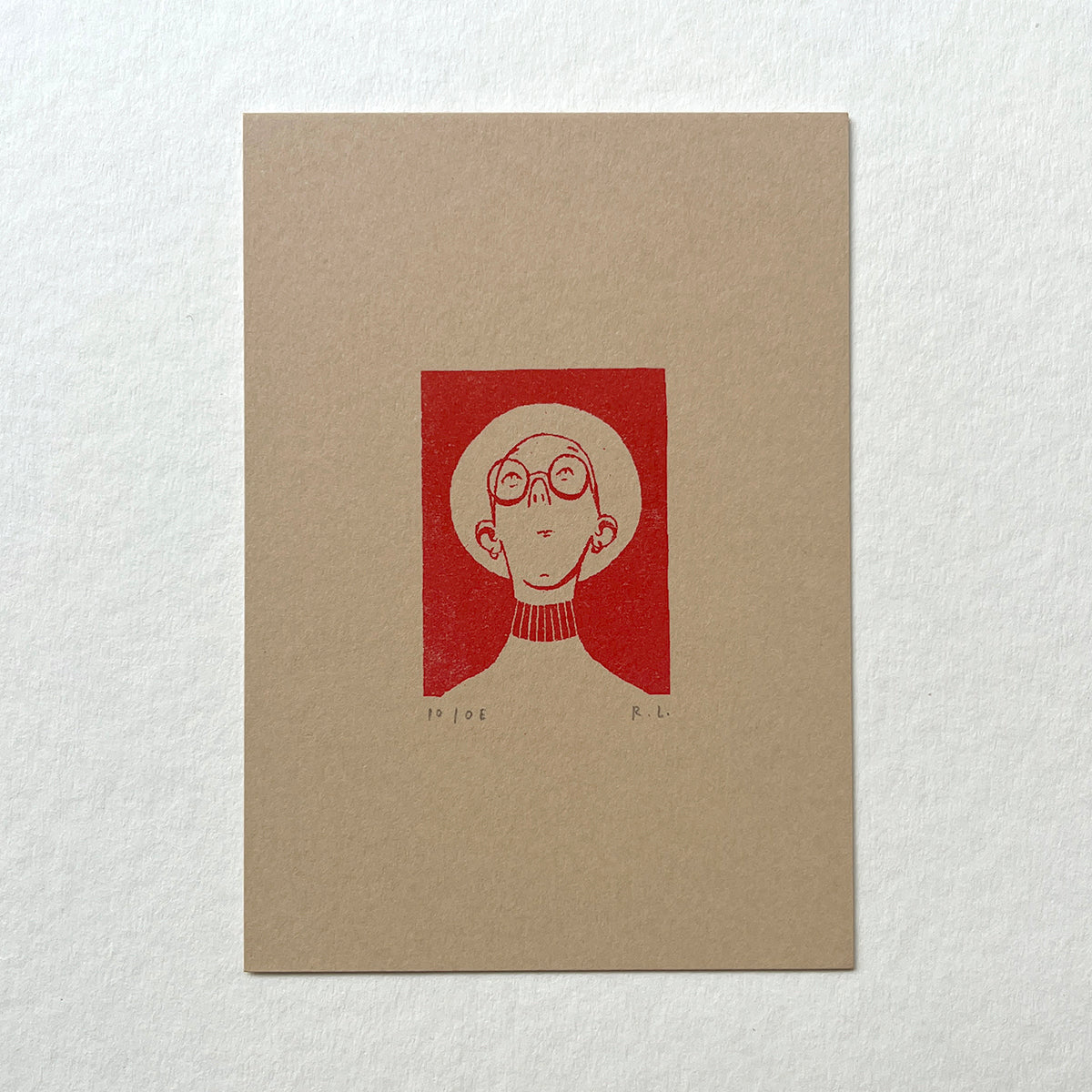 Beige notebook with a red illustration of a person wearing glasses, with a wide-brimmed hat, looking up on a white background