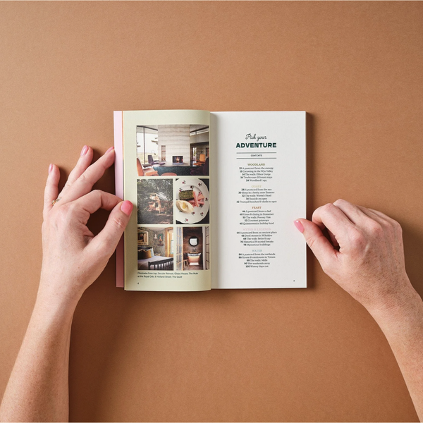 Open book of adventures held by hands on a brown background
