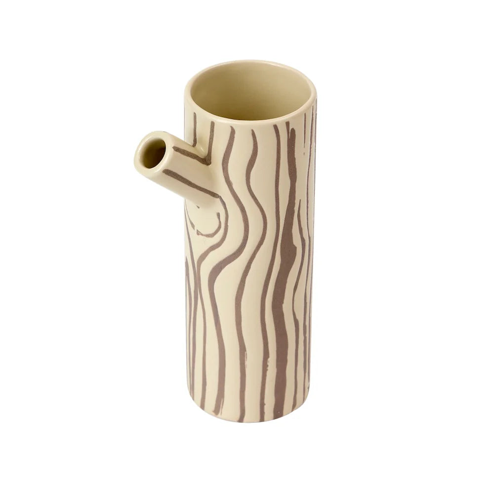 Brown and beige vase in the shape of a log and branch spout with a tree bark design on a white background