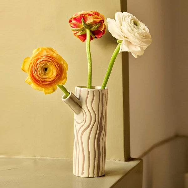 Brown and beige vase in the shape of a log with a tree bark design with three roses on a yellow background