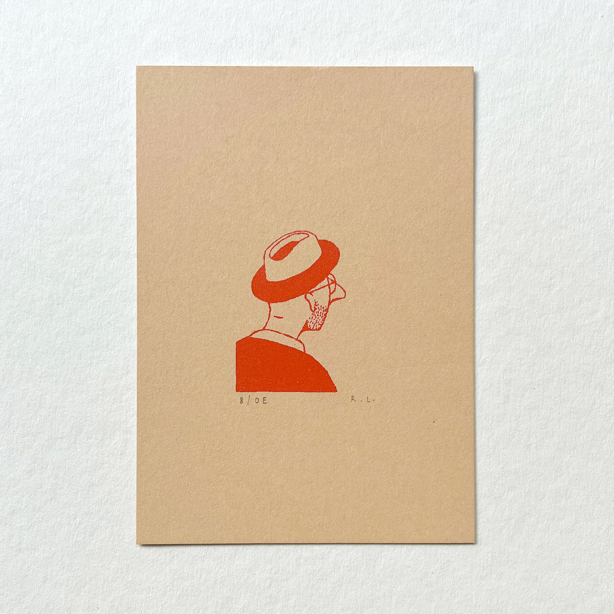 A minimalist art print featuring a red line-art illustration of a man in profile wearing a trilby hat, printed on a square beige card against a textured white background.