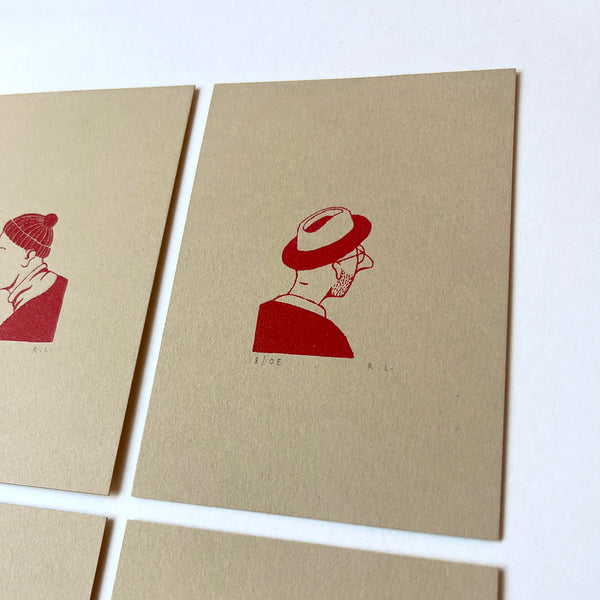 Two beige cards with red illustrations of a person wearing hats on a white background