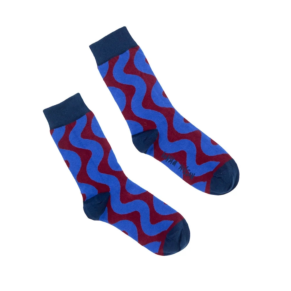 A pair of crew socks with a bold wavy pattern in royal blue and dark red, featuring solid dark navy cuffs, heels, and toes, displayed on a clean white background.