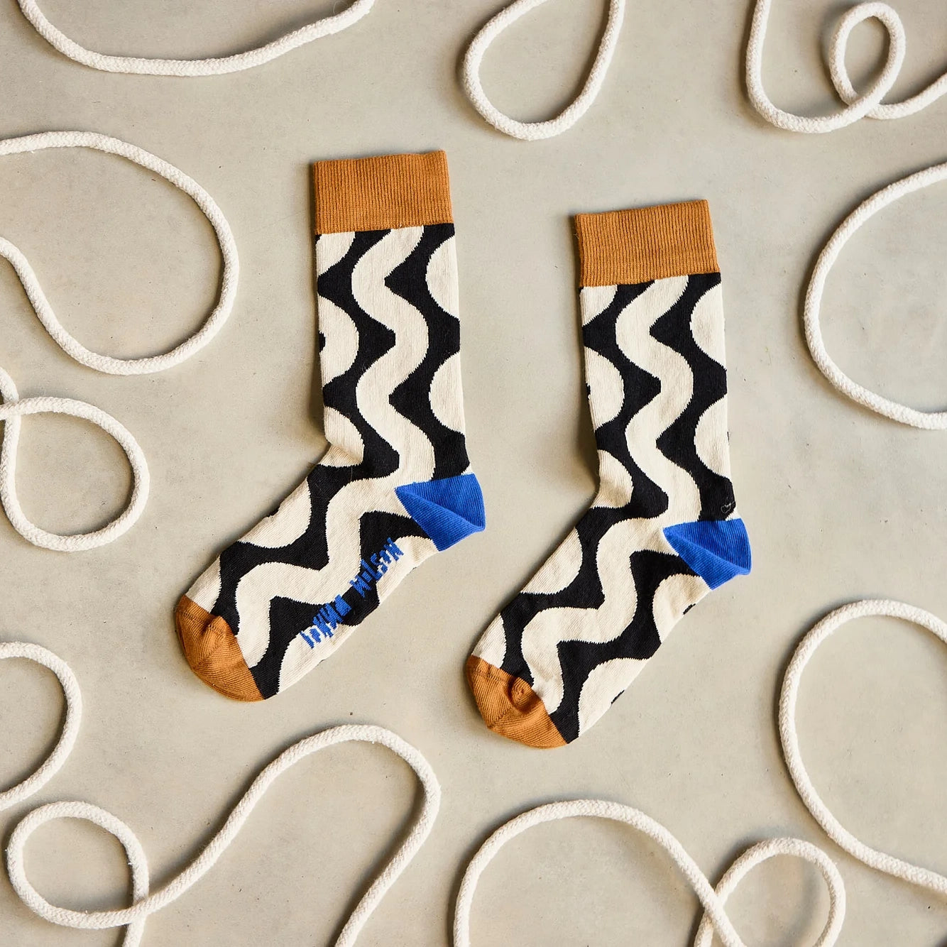 Pair of socks with black and white zigzag pattern and brown accents on a light gray background