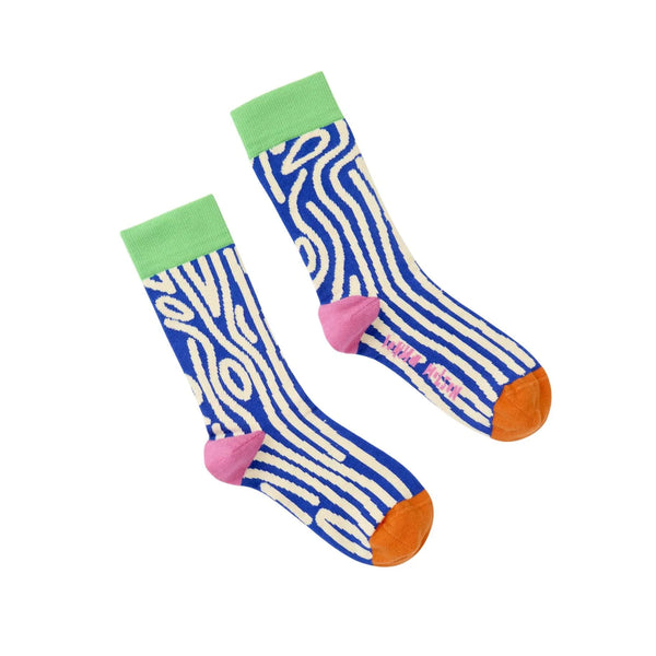 A pair of crew socks with a blue and white wavy wood stripe pattern, featuring a light green cuff, pink heel, and orange toe, displayed on a clean white background.