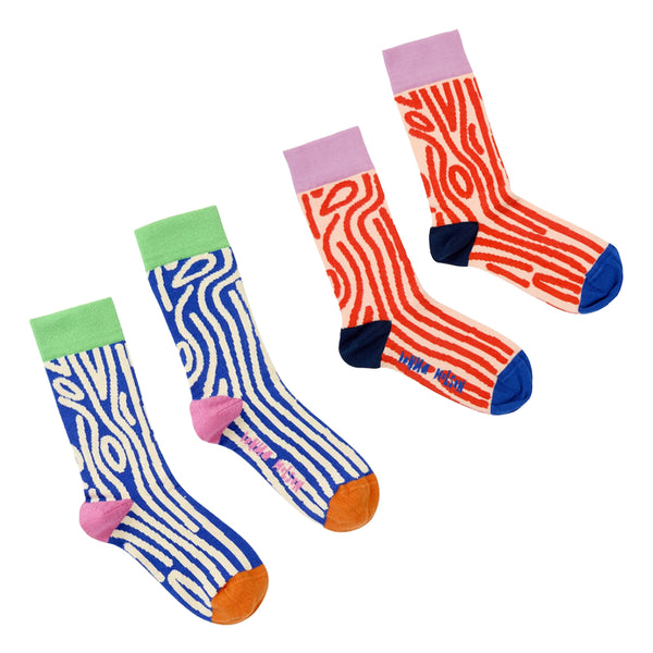 Two pairs of patterned crew socks displayed on a clean white background. The left pair features wavy blue and white woody stripes with pink heels and orange toes.