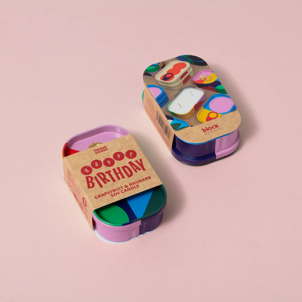 Two colorful candle tins with 'Happy Birthday' text on a white background