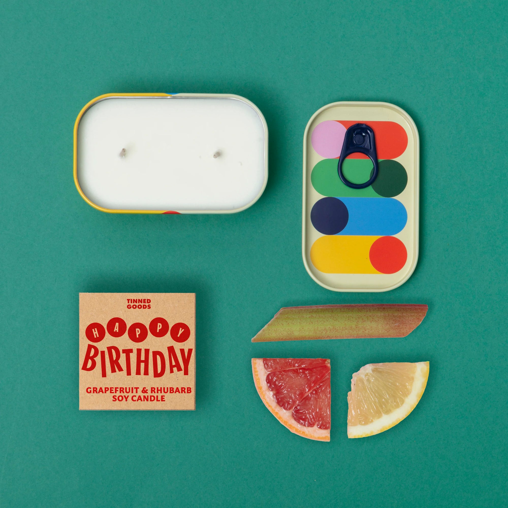 Grapefruit and rhubarb soy candle with geometric tin packaging on a teal background