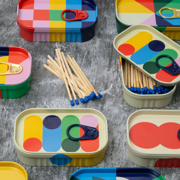Coluorful matchbox tins with matches on a grey surface