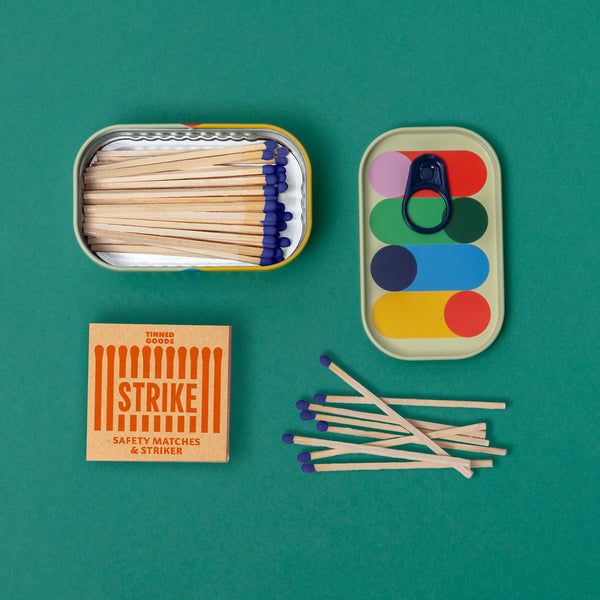 A colourful tin with matches inside on a green background